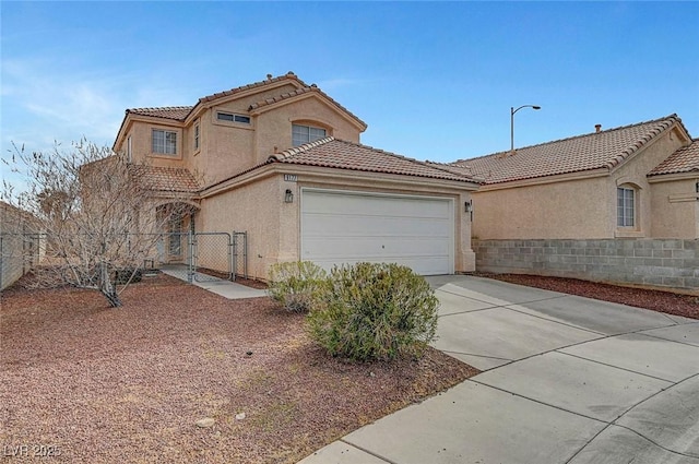 mediterranean / spanish house featuring a tiled roof, concrete driveway, stucco siding, a garage, and a gate