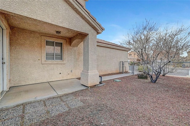 view of side of property with stucco siding, a patio, and fence