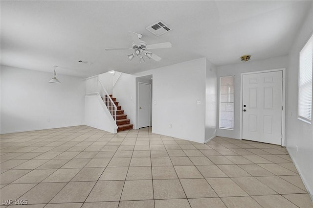 unfurnished living room with light tile patterned flooring, visible vents, stairway, and a ceiling fan