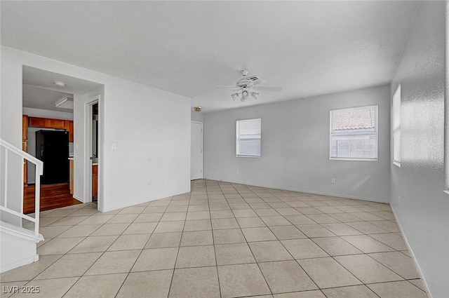 spare room with stairs, light tile patterned floors, and ceiling fan