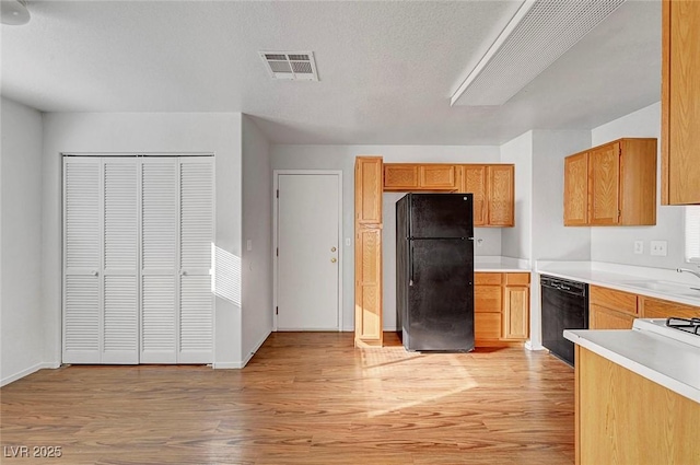 kitchen with black appliances, light countertops, visible vents, and light wood finished floors