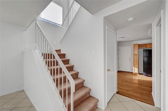 stairway featuring visible vents and tile patterned flooring