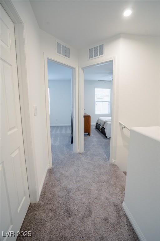 hallway with visible vents, baseboards, and carpet floors