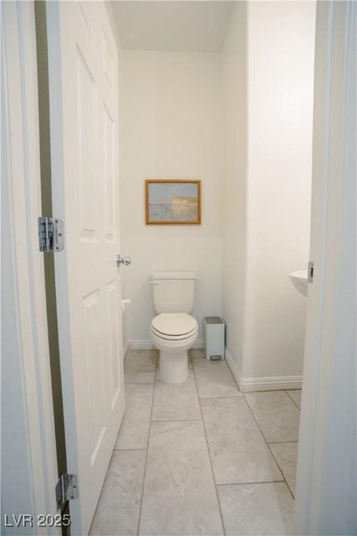 bathroom featuring tile patterned floors, baseboards, and toilet