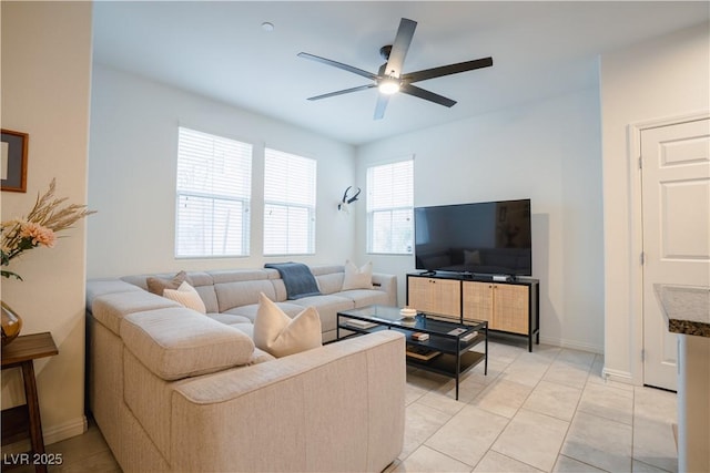 living area with light tile patterned flooring, baseboards, and ceiling fan