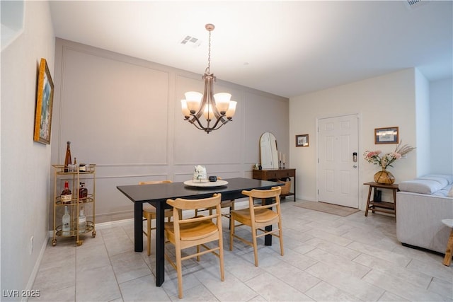 dining area featuring light tile patterned flooring, a decorative wall, visible vents, and an inviting chandelier