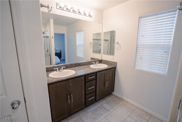 ensuite bathroom with double vanity, connected bathroom, baseboards, and a sink