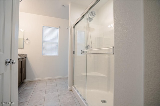 bathroom featuring tile patterned floors, baseboards, a shower stall, and vanity