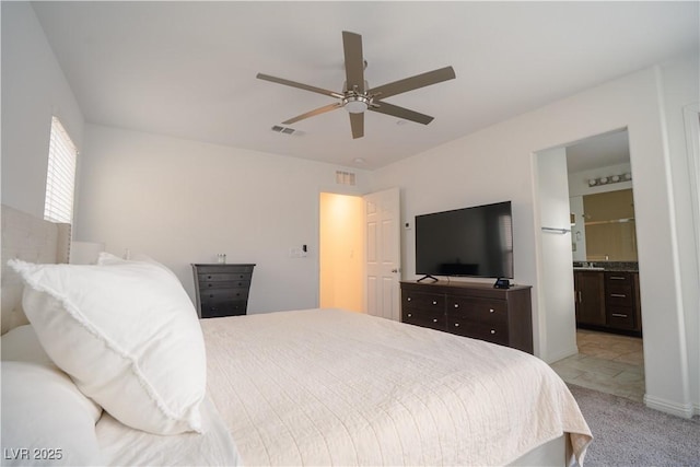 bedroom with a ceiling fan, light colored carpet, visible vents, and connected bathroom