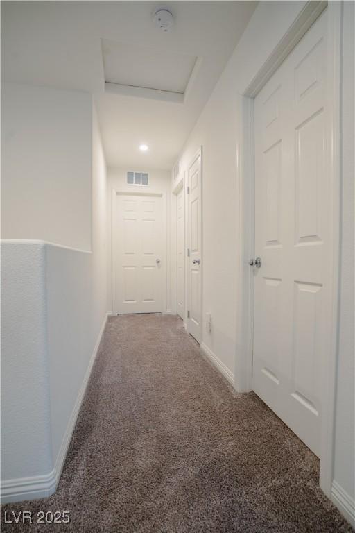 hallway with baseboards, visible vents, carpet floors, and attic access