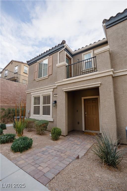 view of front of house featuring a tile roof, a balcony, and stucco siding