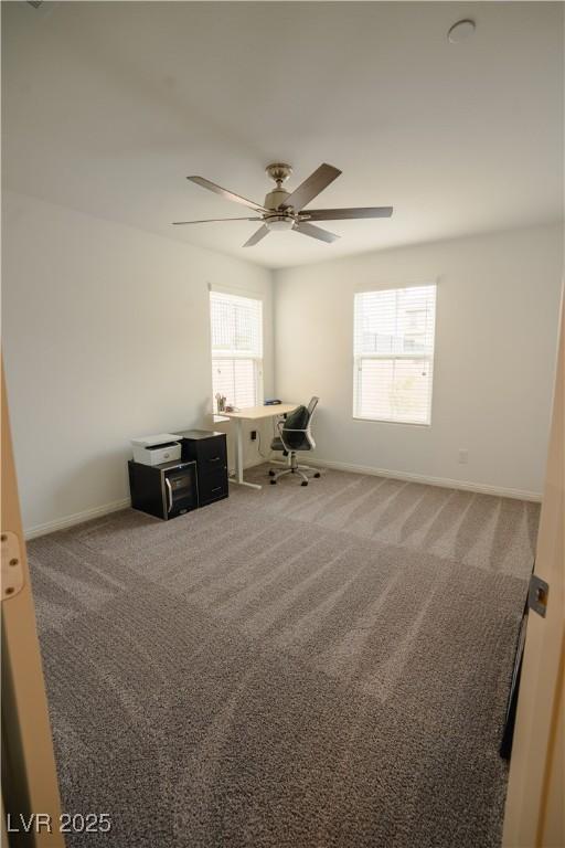 unfurnished office featuring carpet flooring, baseboards, and ceiling fan