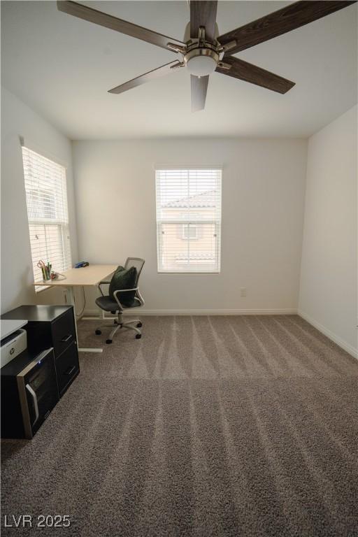 unfurnished office featuring plenty of natural light, baseboards, carpet floors, and ceiling fan