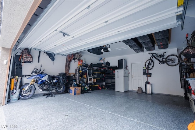 garage featuring a garage door opener and freestanding refrigerator