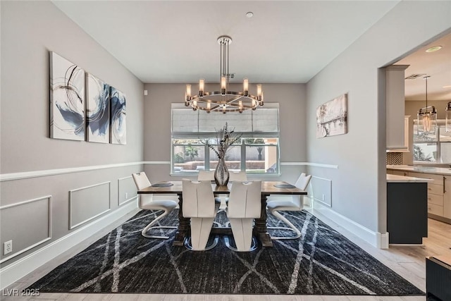 dining space with a decorative wall, plenty of natural light, a wainscoted wall, and a chandelier