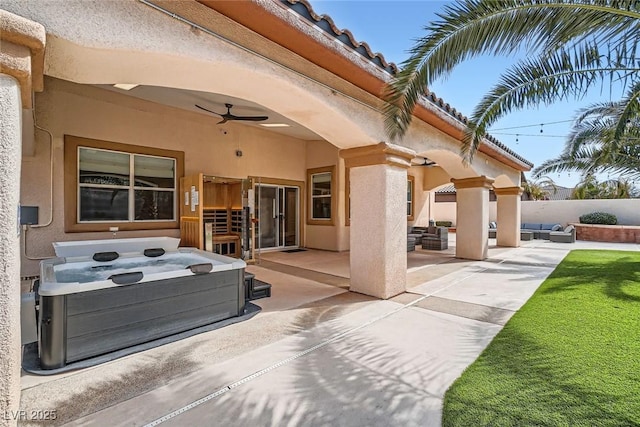 view of patio with a hot tub, ceiling fan, and fence