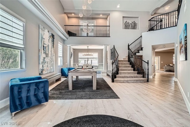 foyer with a wealth of natural light, stairs, an inviting chandelier, and wood finished floors