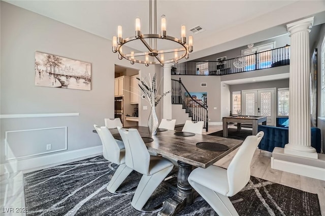 dining space with wood finished floors, baseboards, visible vents, ornate columns, and a chandelier