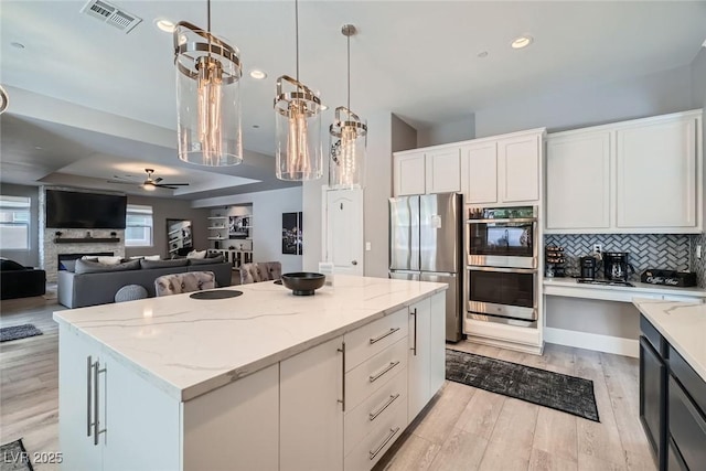 kitchen with tasteful backsplash, a center island, stainless steel appliances, light wood-style floors, and ceiling fan