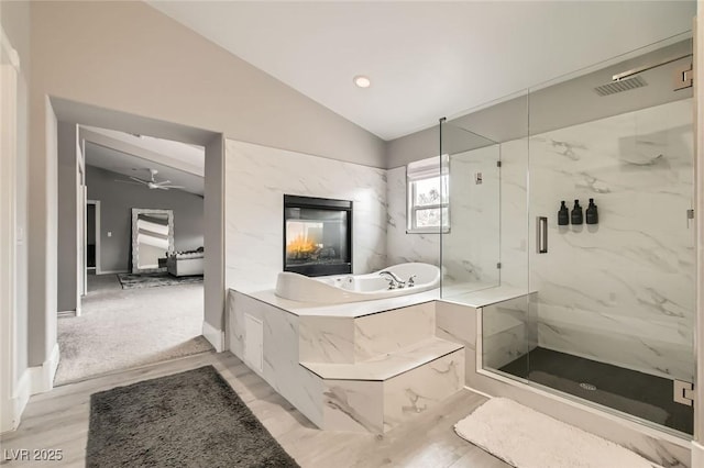 bathroom with a ceiling fan, a marble finish shower, baseboards, a bath, and vaulted ceiling