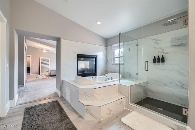 bathroom with a marble finish shower, baseboards, vaulted ceiling, a bath, and a ceiling fan