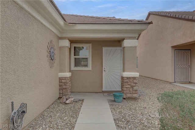 entrance to property with a tile roof and stucco siding