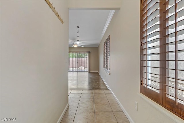 hallway featuring crown molding, light tile patterned floors, and baseboards