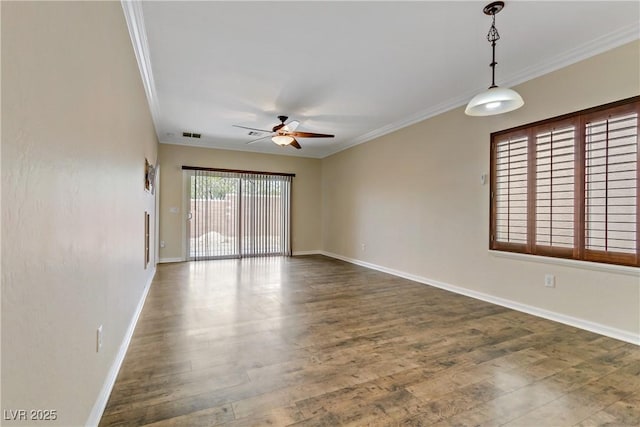 spare room featuring wood finished floors, visible vents, baseboards, ornamental molding, and ceiling fan