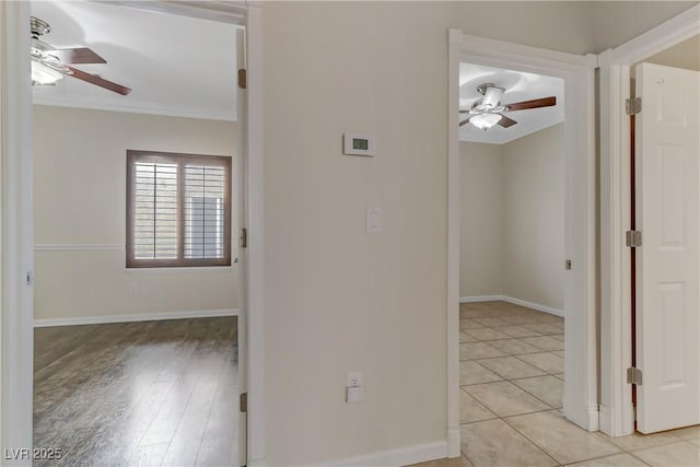 hall with crown molding, light tile patterned floors, and baseboards