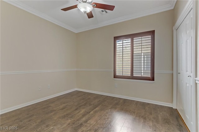 empty room with visible vents, a ceiling fan, wood finished floors, crown molding, and baseboards