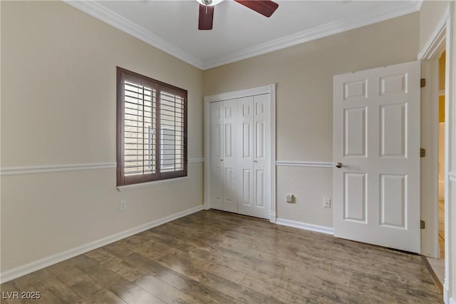 unfurnished bedroom featuring wood finished floors, a closet, crown molding, baseboards, and ceiling fan