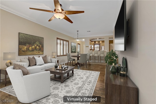 living area featuring a ceiling fan, visible vents, wood finished floors, baseboards, and ornamental molding