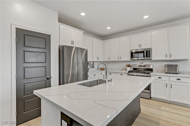 kitchen with recessed lighting, a sink, white cabinets, light wood-style floors, and appliances with stainless steel finishes