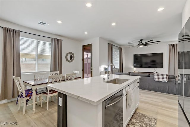 kitchen featuring visible vents, dishwasher, an island with sink, white cabinetry, and a sink