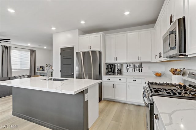 kitchen featuring a sink, light wood-style floors, appliances with stainless steel finishes, and white cabinetry