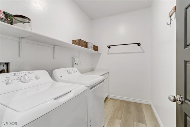 clothes washing area featuring washing machine and clothes dryer, cabinet space, light wood-style flooring, and baseboards