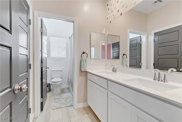 bathroom featuring double vanity, visible vents, toilet, and a sink