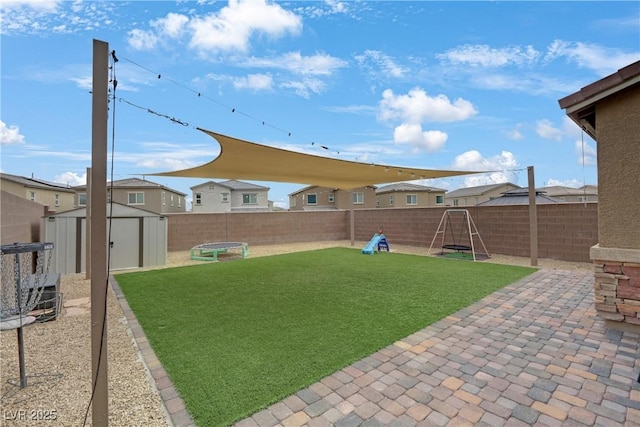 view of yard with a storage shed, an outbuilding, a fenced backyard, and a patio area