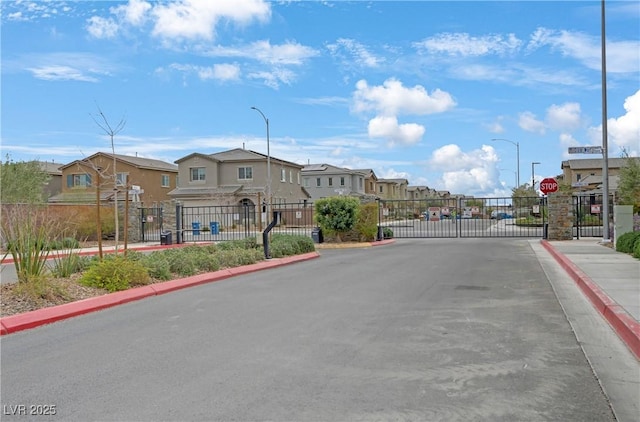 view of road with traffic signs, a residential view, curbs, and a gate