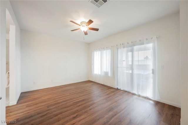 empty room featuring wood finished floors, a ceiling fan, visible vents, and baseboards