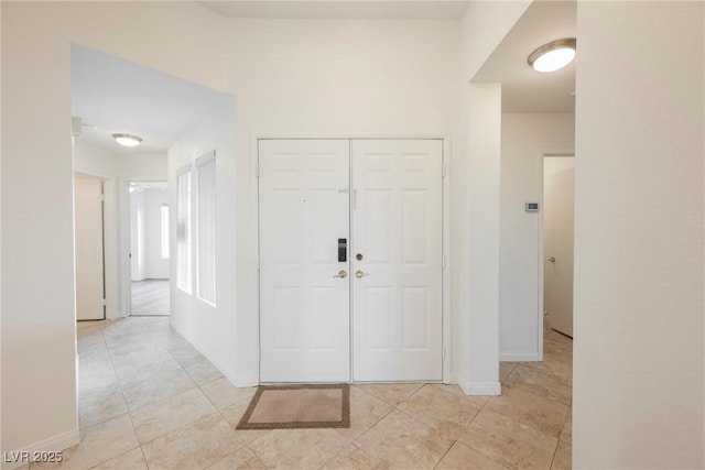 foyer entrance with light tile patterned floors and baseboards