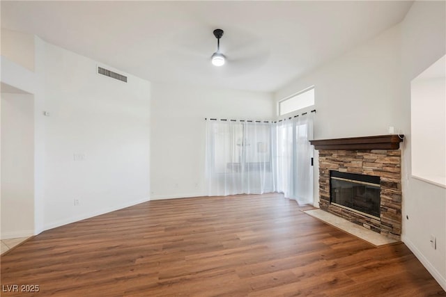 unfurnished living room with visible vents, baseboards, a fireplace, wood finished floors, and a ceiling fan