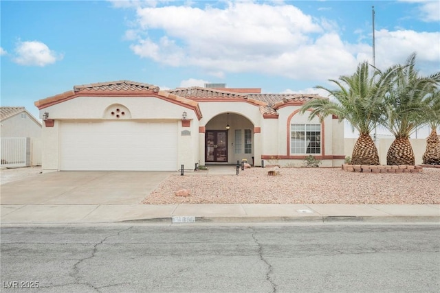 mediterranean / spanish home with stucco siding, driveway, a tile roof, and a garage