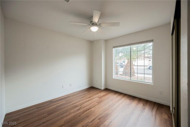 empty room featuring a ceiling fan, wood finished floors, and baseboards