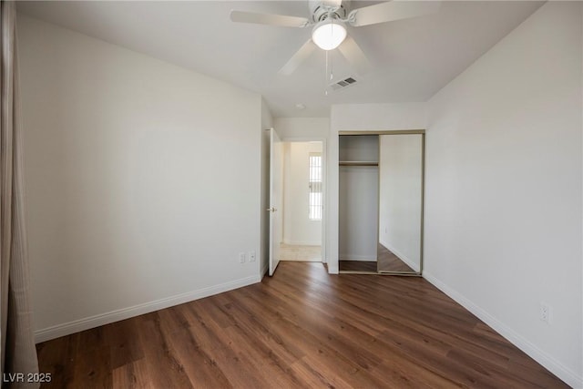 unfurnished bedroom featuring wood finished floors, visible vents, a closet, and baseboards