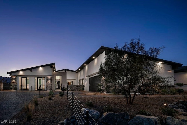 exterior space featuring stucco siding, stone siding, and an attached garage