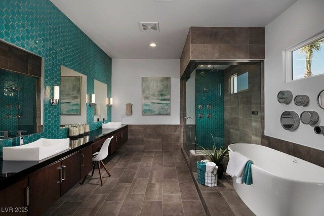 full bathroom featuring visible vents, a sink, tile walls, a shower stall, and a freestanding bath