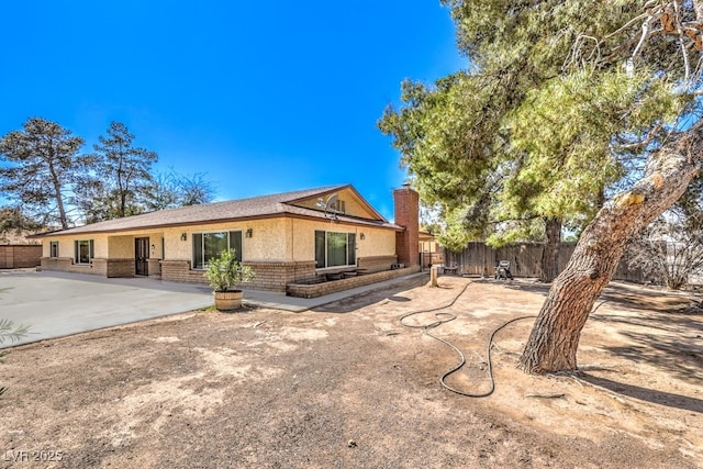 10615 Rancho Destino Rd, Las Vegas, NV 89183 - back of house featuring a patio, fence, brick siding, and a chimney