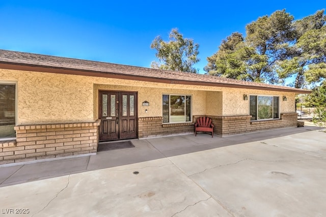 10615 Rancho Destino Rd, Las Vegas, NV 89183 - doorway to property featuring stucco siding, brick siding, and french doors