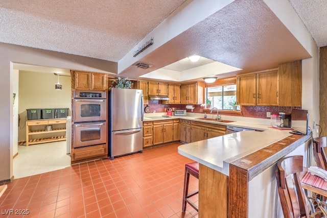 10615 Rancho Destino Rd, Las Vegas, NV 89183 - kitchen with visible vents, a kitchen bar, appliances with stainless steel finishes, a peninsula, and a raised ceiling